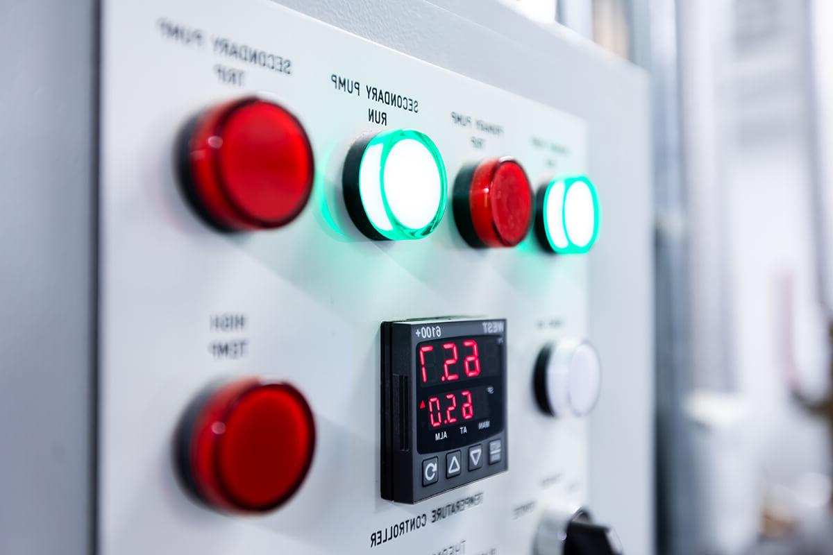A close-up of red and green buttons on a control panel for pump machinery