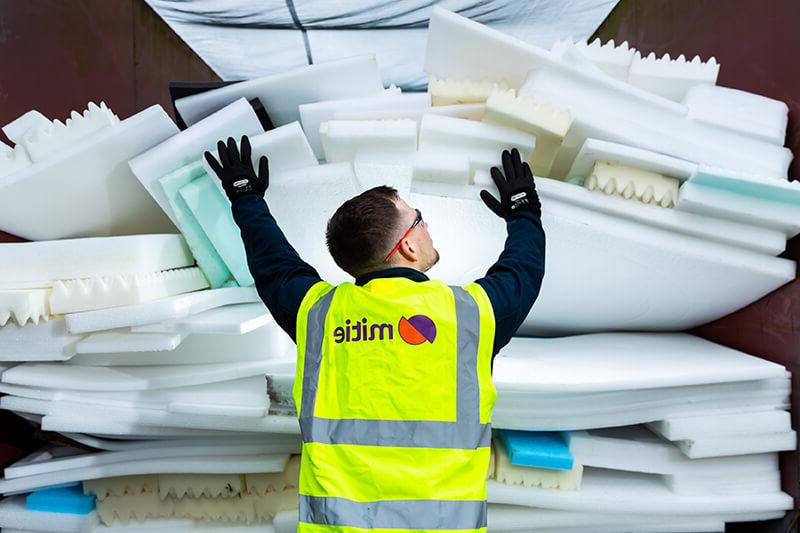 A Mitie employee, wearing a branded high-vis vest, pushing a large amount of foam and polystyrene waste